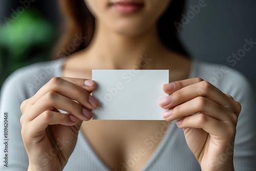 Close up of a woman's hand holding a blank business card. Mockup
