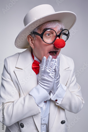Surprised clown with gloved hands near his face.