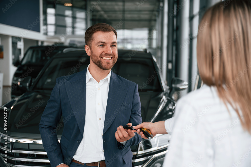 Businessman and woman are in a car dealership Businessman and woman are in a car dealership
