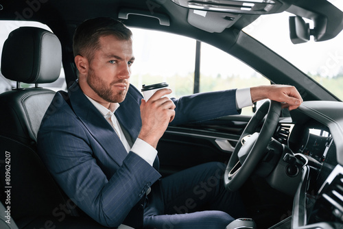 Driving and drinking coffee. Businessman is in the brand new car © standret