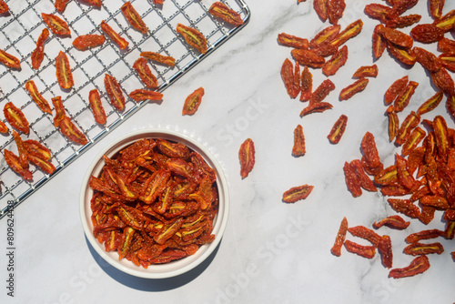 dried cherry tomatoes in white ceramic bowl on white marble table background.