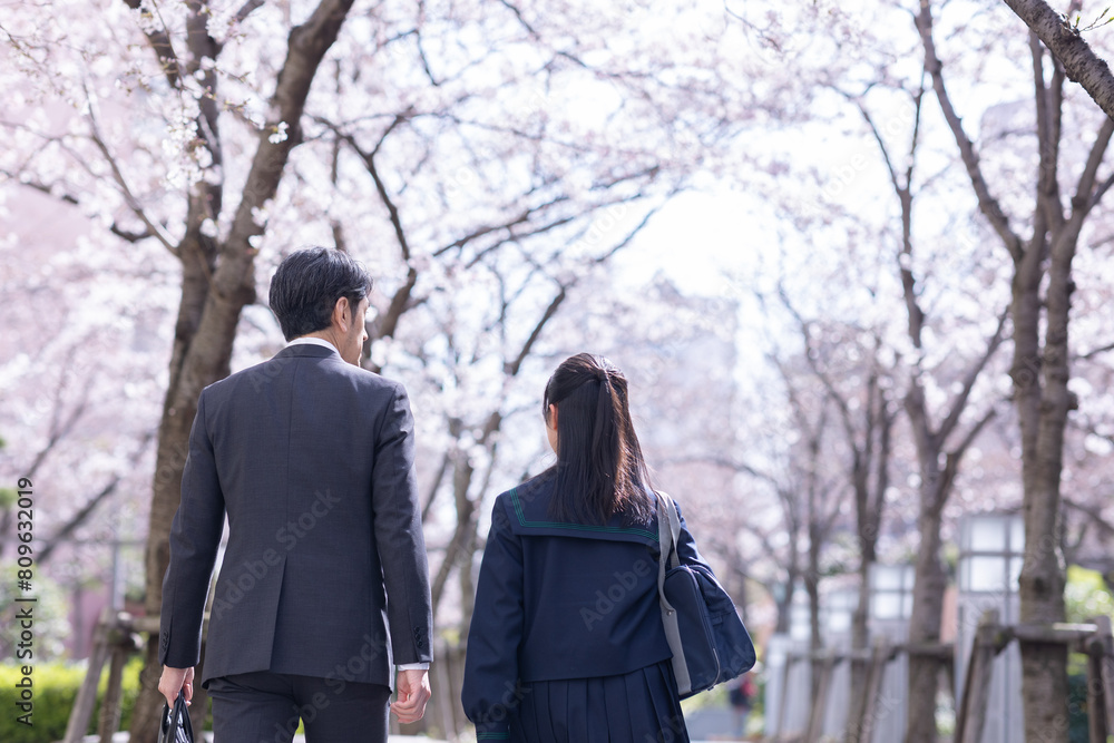 桜並木の下を歩く親子