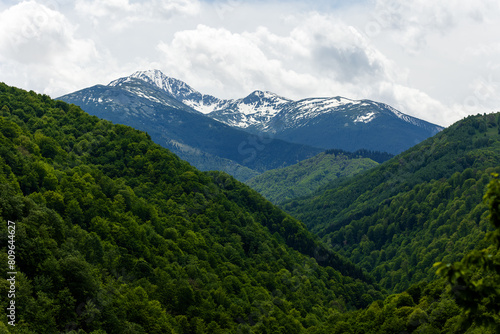 Snowy peaks of Retezat Mountains in Transylvania, Romania, seen from a hill top  photo