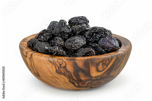 a wooden bowl filled with raisins on a white surface