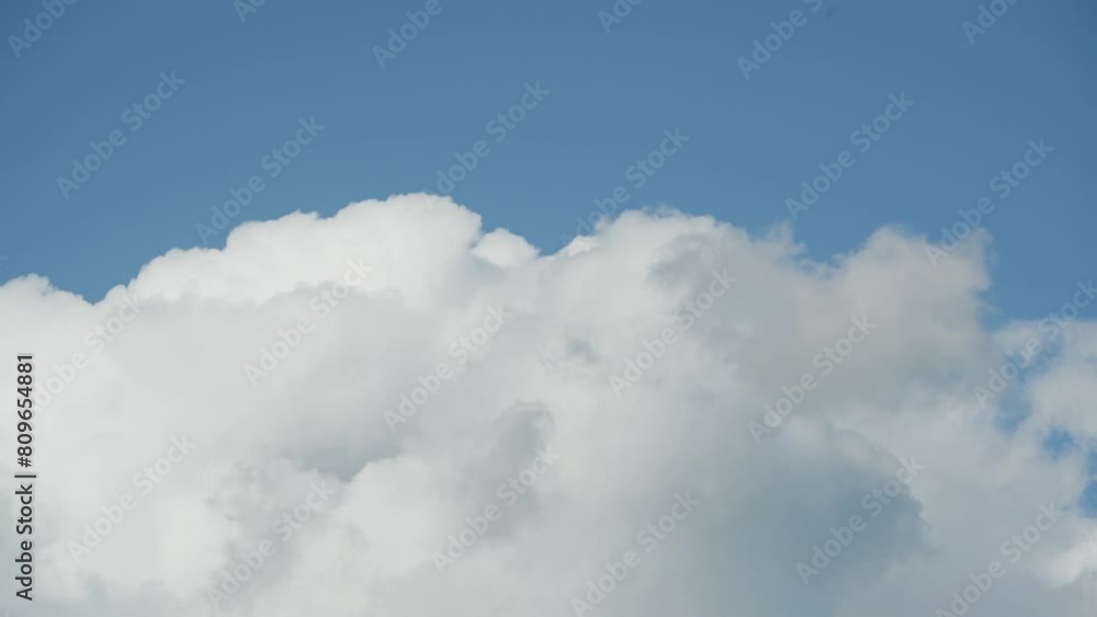 Fluffy white clouds move swiftly across a bright blue sky in a timelapse Fluffy white clouds move swiftly across a bright blue sky in a timelapse