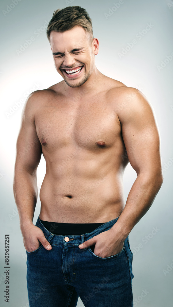 Shirtless man, laugh and muscles in studio with jeans for confidence, physical training or workout results on white background. Body, funny and model for bodybuilder abs, chest or transformation Shirtless man, laugh and muscles in studio with jeans for confidence, physical training or workout results on white background. Body, funny and model for bodybuilder abs, chest or transformation