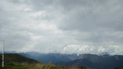 timelapse con visuale dettagliata di un panorama di montagna nel nord est Italia, visto dall'alto, durante un pomeriggio di primavera con un cielo nuvoloso e minaccioso photo