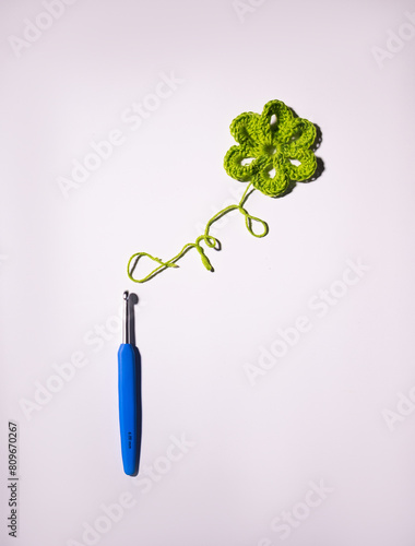 Handmade knitted flower and crochet hook on a white background photo