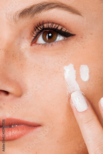 Cropped young beautiful woman with healthy skin taking care of face with cream. Close up portrait. photo