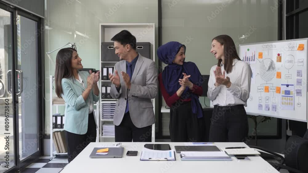 A diverse team, including a middle-aged Asian businessman, Caucasian young businesswoman, Muslim hijab-wearing middle-aged businesswoman, meets in a boardroom to close an Annual General Meeting. A diverse team, including a middle-aged Asian businessman, Caucasian young businesswoman, Muslim hijab-wearing middle-aged businesswoman, meets in a boardroom to close an Annual General Meeting.