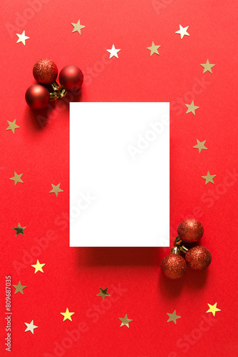 Blank greeting card. Christmas and new year composition with Christmas red balls and gold confetti stars. Red background. Top view, flat lay. Empty space for copy space