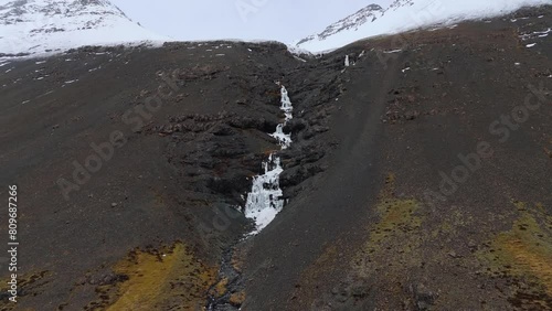 Frozen Skutafoss waterfall cascading from snowy glacier mountains. photo