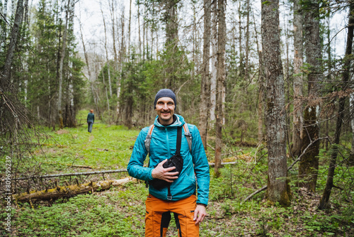 Man, camera, smiling among trees, capturing natural landscape at forest
