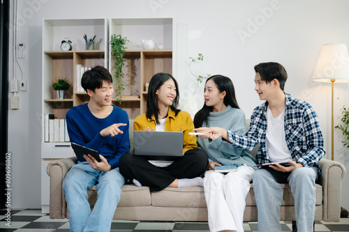 Group of young Asian college students working on his project assignment, using laptop computer and tablet an online informations. together, enjoy talking