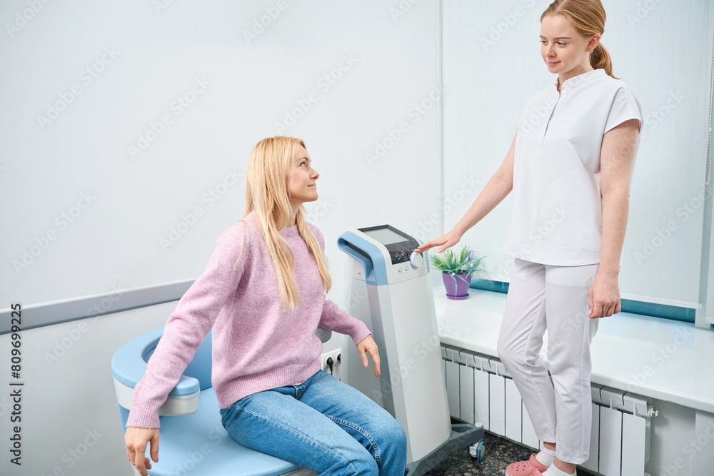 Woman with lower back area problems preparing for electromagnetic stimulation Woman with lower back area problems preparing for electromagnetic stimulation