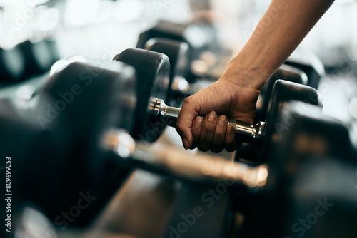 Slika na platnu Close-up of a female hand picking up a heavy dumbbell.