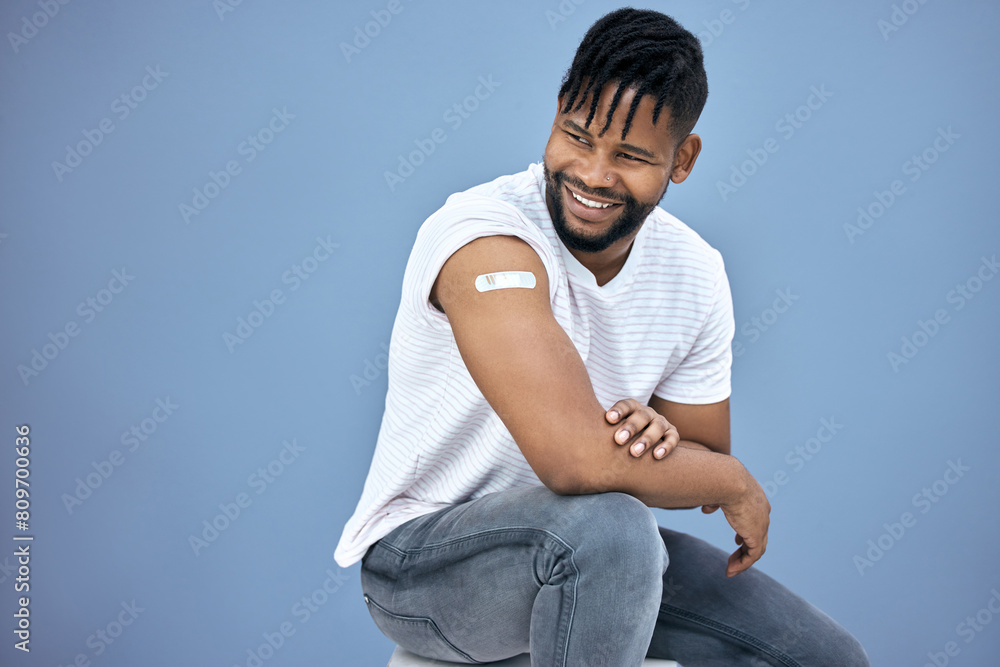 Vaccine, healthcare and black man with plaster in studio for flu, disease or illness prevention. Smile, wellness and African male person with bandaid for medical immunization by gray background. Vaccine, healthcare and black man with plaster in studio for flu, disease or illness prevention. Smile, wellness and African male person with bandaid for medical immunization by gray background.
