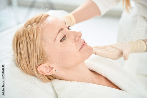 Woman cosmetician preparing adult woman client for therapy photo