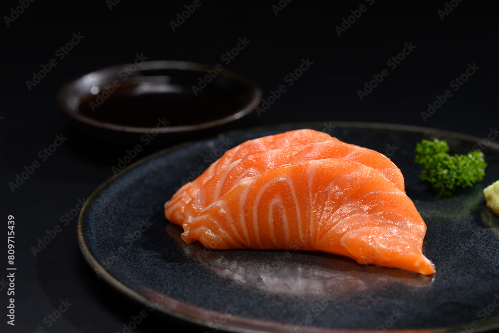 Close up sliced salmon sashimi serve on black plate with parsley leaf. Japanese food style Close up sliced salmon sashimi serve on black plate with parsley leaf. Japanese food style