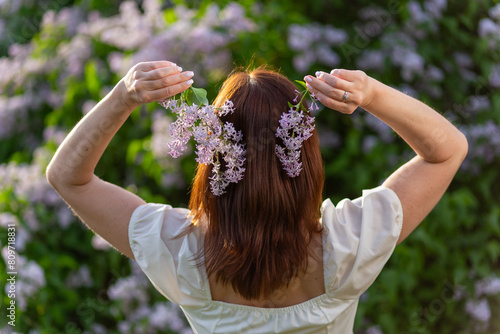 A girl with loose hair holds lilac flowers in her hands