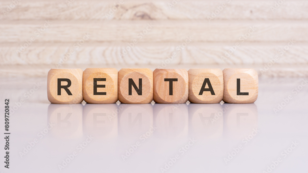 wooden blocks displaying the word 'RENTAL' arranged on a glossy gray surface wooden blocks displaying the word 'RENTAL' arranged on a glossy gray surface