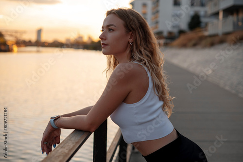 Beautiful woman in sport suit for fitness relaxing after exercises on the street. Concept of healthy lifestyle, sport, urban life