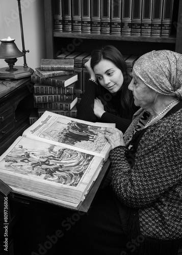 Obraz na płótnie Foto scattata ad una nonna con sua nipote mentre leggono una raccolta di libri antichi. w salonie