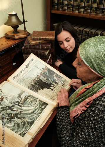 Obraz na płótnie Foto scattata ad una nonna con sua nipote mentre leggono una raccolta di libri antichi. w salonie