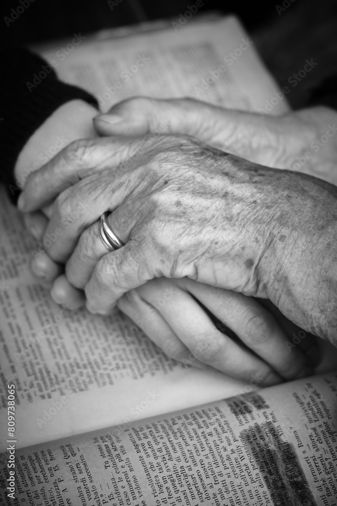 Foto scattata alle mani di una nonna e di una nipote unite sopra una raccolta di libri antichi.