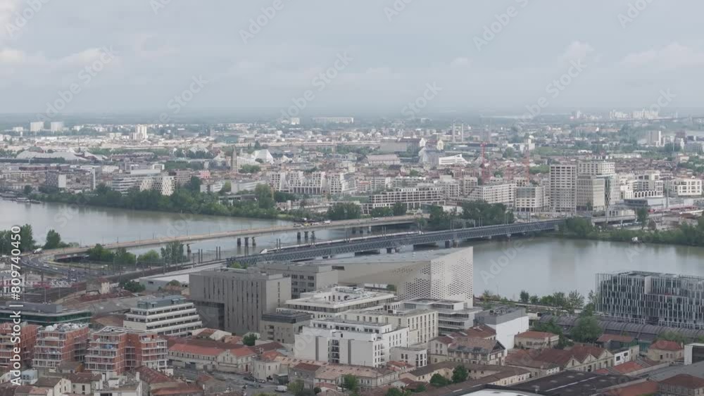 TGV high-speed train crossing the Passerelle Eiffel bridge going over the Garonne River to train station and St. Jean bridge behind it in Bordeaux France, Aerial pan left shot TGV high-speed train crossing the Passerelle Eiffel bridge going over the Garonne River to train station and St. Jean bridge behind it in Bordeaux France, Aerial pan left shot
