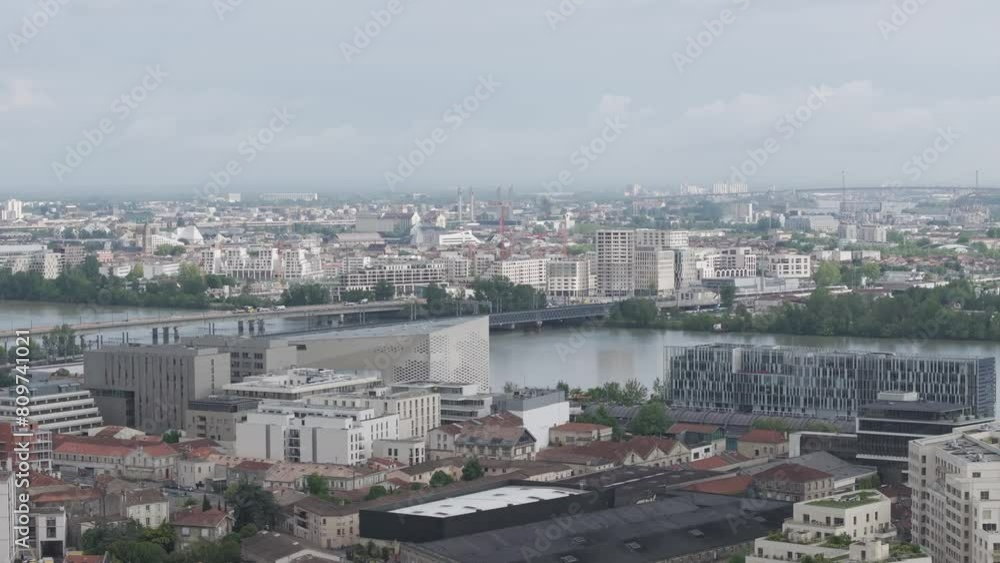 The Meca cultural center and high-speed train arriving at station over Passerelle Eiffel bridge crossing the Garonne River in Bordeaux France, Aerial rising reveal shot The Meca cultural center and high-speed train arriving at station over Passerelle Eiffel bridge crossing the Garonne River in Bordeaux France, Aerial rising reveal shot
