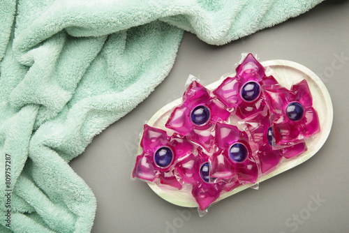 Laundry capsules with mint towel on grey background. Laundry detergent for washing clothes in a washing machine. photo