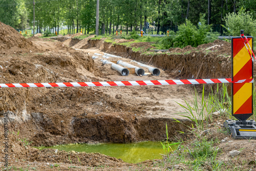 Wallpaper Mural New fiber glass water pipeline in trench. Replacement of old rusty tubes by new one, surrounding with Red white warning tape barrier ribbon swinging in the wind Torontodigital.ca