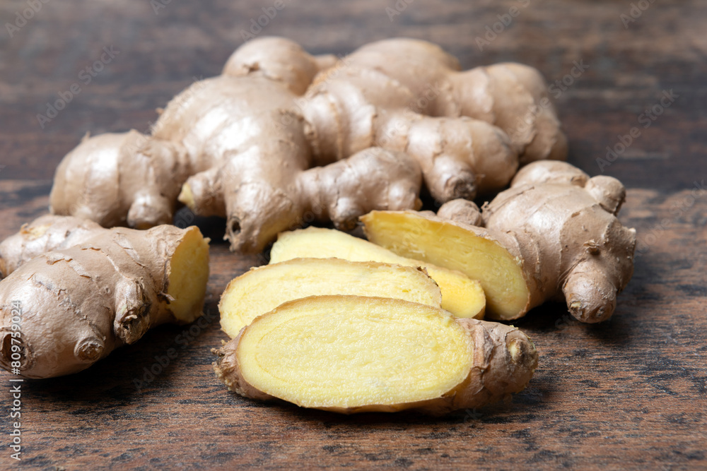 Fresh ginger root on wooden table, close up of slices in front Fresh ginger root on wooden table, close up of slices in front