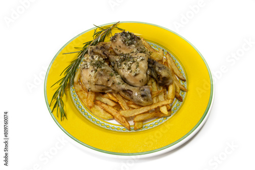 Garlic chicken thighs with French fries, served on a yellow plate, with a sprig of rosemary. Isolated on a white background. Spanish food concept.