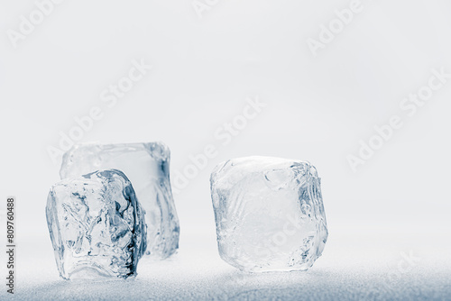 Natural ice cubes on a white frosty shiny surface.