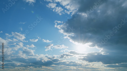 Beautiful sunny blue sky with bright sun light shining through white clouds. Timelapse.