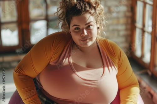 A woman with a large bust is sitting in a pink and yellow shirt
