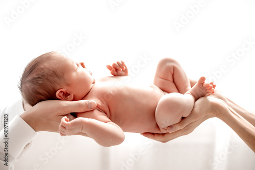 a newborn baby boy gently holding mom's and dad's hands on a white isolated window background at home, a happy family with a child