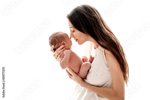 a mother with a newborn baby boy hugs and kisses gently holding him in her arms on a white isolated background of a house window