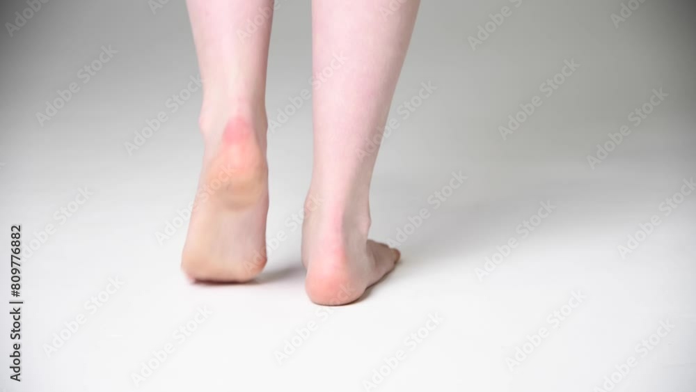 Close-up rear view of barefoot woman standing on white floor and training her dance moves. Female heels towards the camera. Soft focus. Real time handheld video. Beauty and skin care theme. Close-up rear view of barefoot woman standing on white floor and training her dance moves. Female heels towards the camera. Soft focus. Real time handheld video. Beauty and skin care theme.