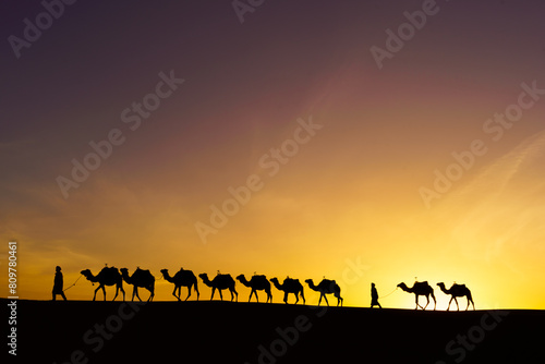 Obraz na płótnie Sunrise silhouette of camels and handler, Merzouga w salonie