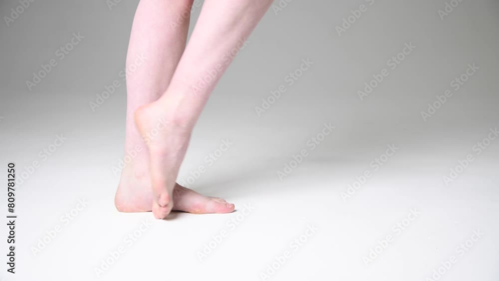 Close-up side view of barefoot caucasian woman standing on white floor and training her dance moves. Soft focus. Real time handheld video. Hobby, leisure and body care theme. Close-up side view of barefoot caucasian woman standing on white floor and training her dance moves. Soft focus. Real time handheld video. Hobby, leisure and body care theme.