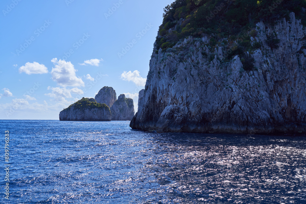 The coastline of the island of Capri, with Faraglioni di Capri rock formations in the background, Campanian Archipelago, Italy
