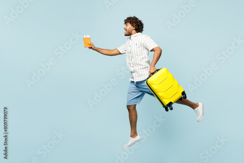 Full body traveler Indian man in white casual clothes hold passport ticket bag jump high run isolated on plain blue background Tourist travel abroad in free time rest getaway Air flight trip concept #809799079