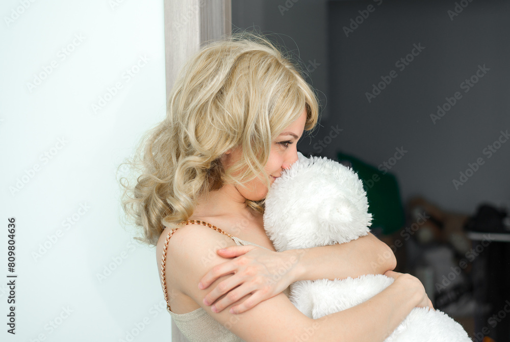 A beautiful girl is holding a white toy, possibly a polar bear. She smiles and she is happy. A beautiful girl is holding a white toy, possibly a polar bear. She smiles and she is happy.