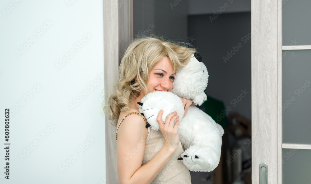 A beautiful girl is holding a white toy, possibly a polar bear. She smiles and she is happy. A beautiful girl is holding a white toy, possibly a polar bear. She smiles and she is happy.
