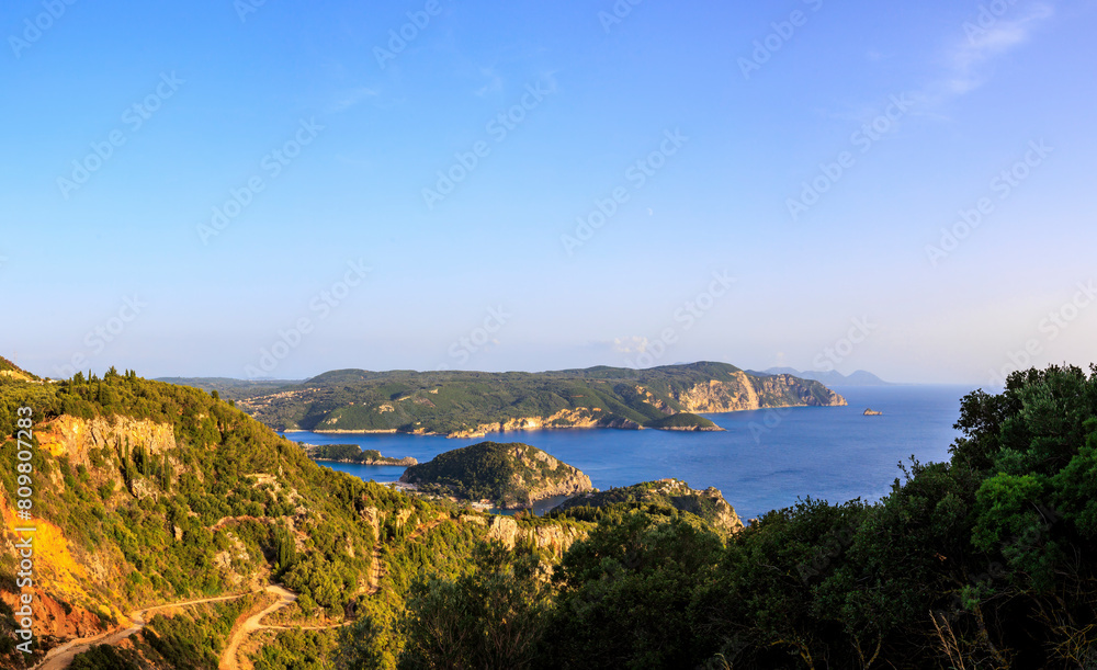 View in the evening under a blue sky over the bay and the sea at Paleokastrtitsa on the island of Corfu View in the evening under a blue sky over the bay and the sea at Paleokastrtitsa on the island of Corfu