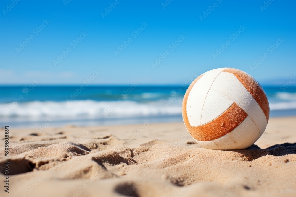 A beach ball is sitting on the sand near the water
