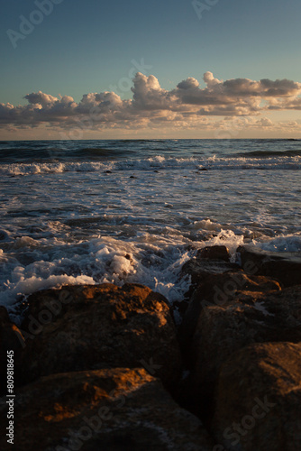Ocean waves gently kiss sandy shore under twilight sky.